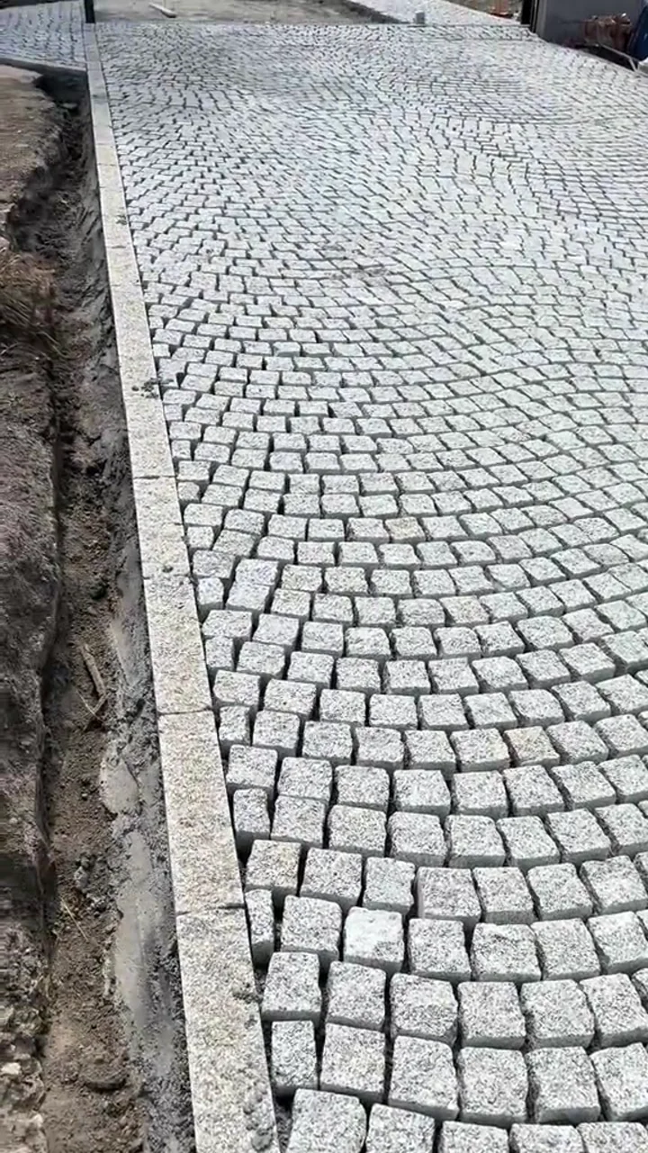 Šira staza od svetle kamene kocke izvedena u pravilnim lučnim redovima